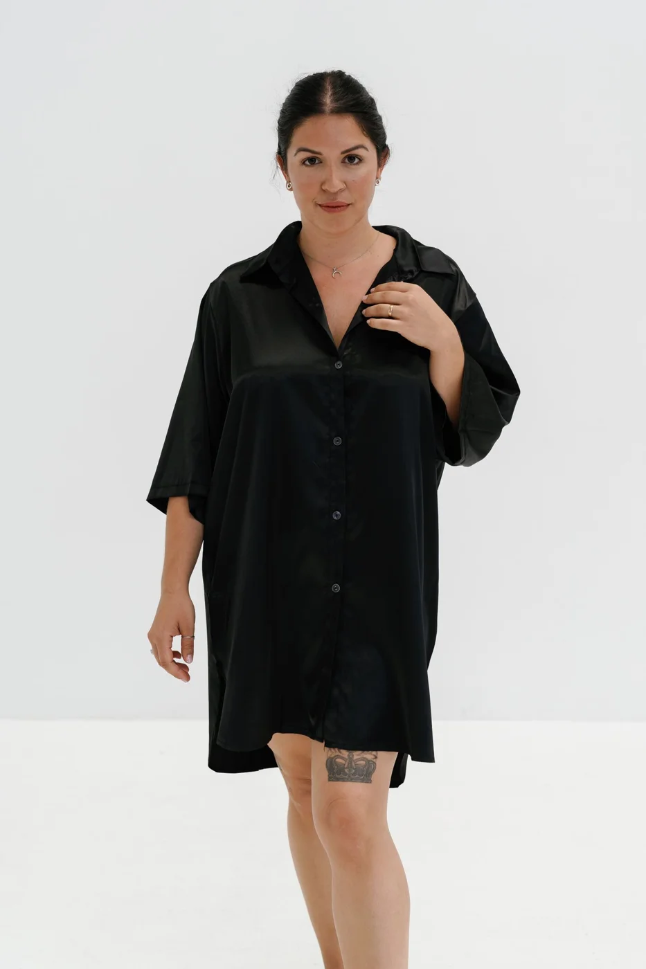 A woman in a black shirt dress poses for a photo