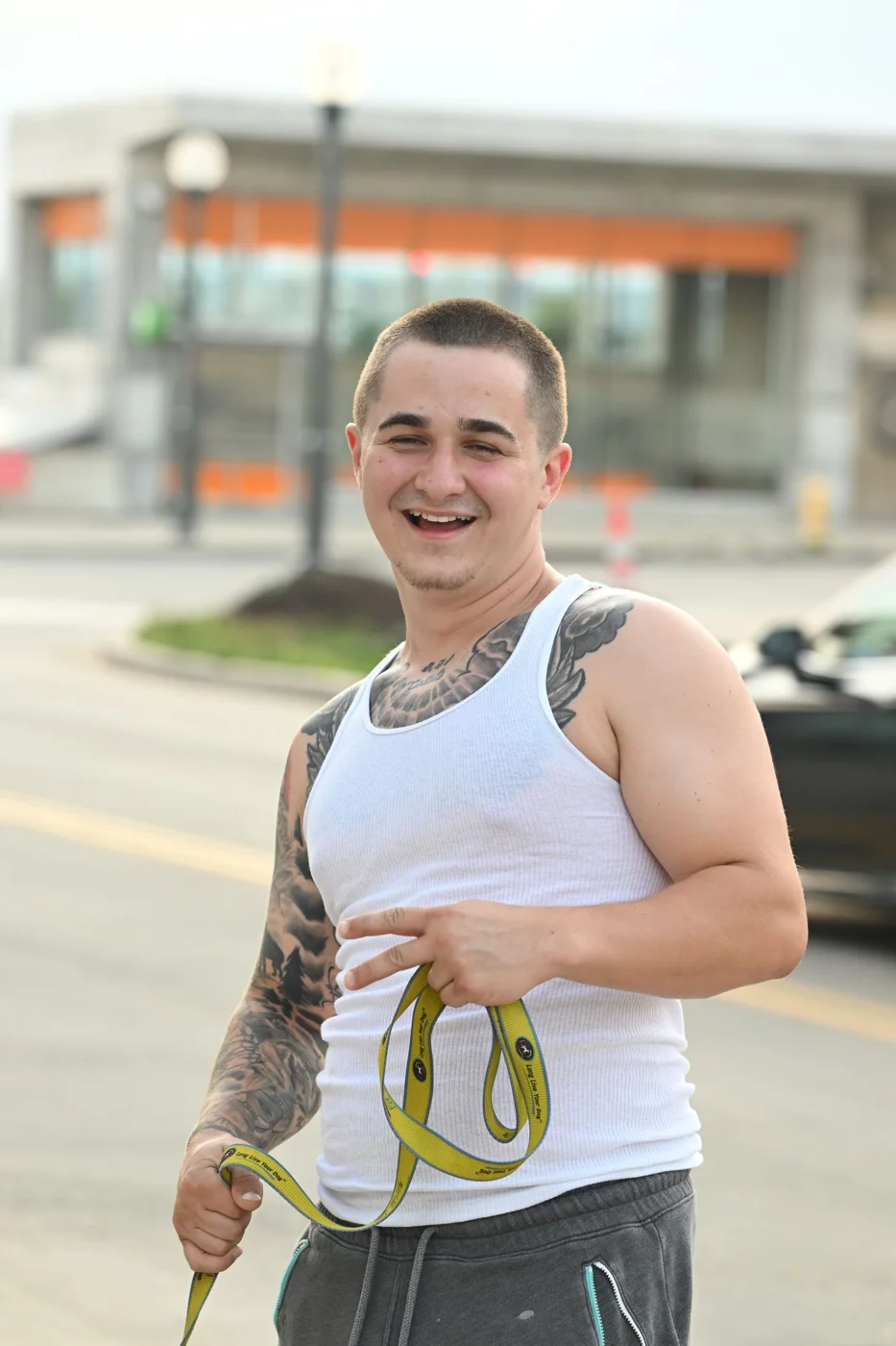 A Tattooed Man in White Undershirt Doing a Peace Sign