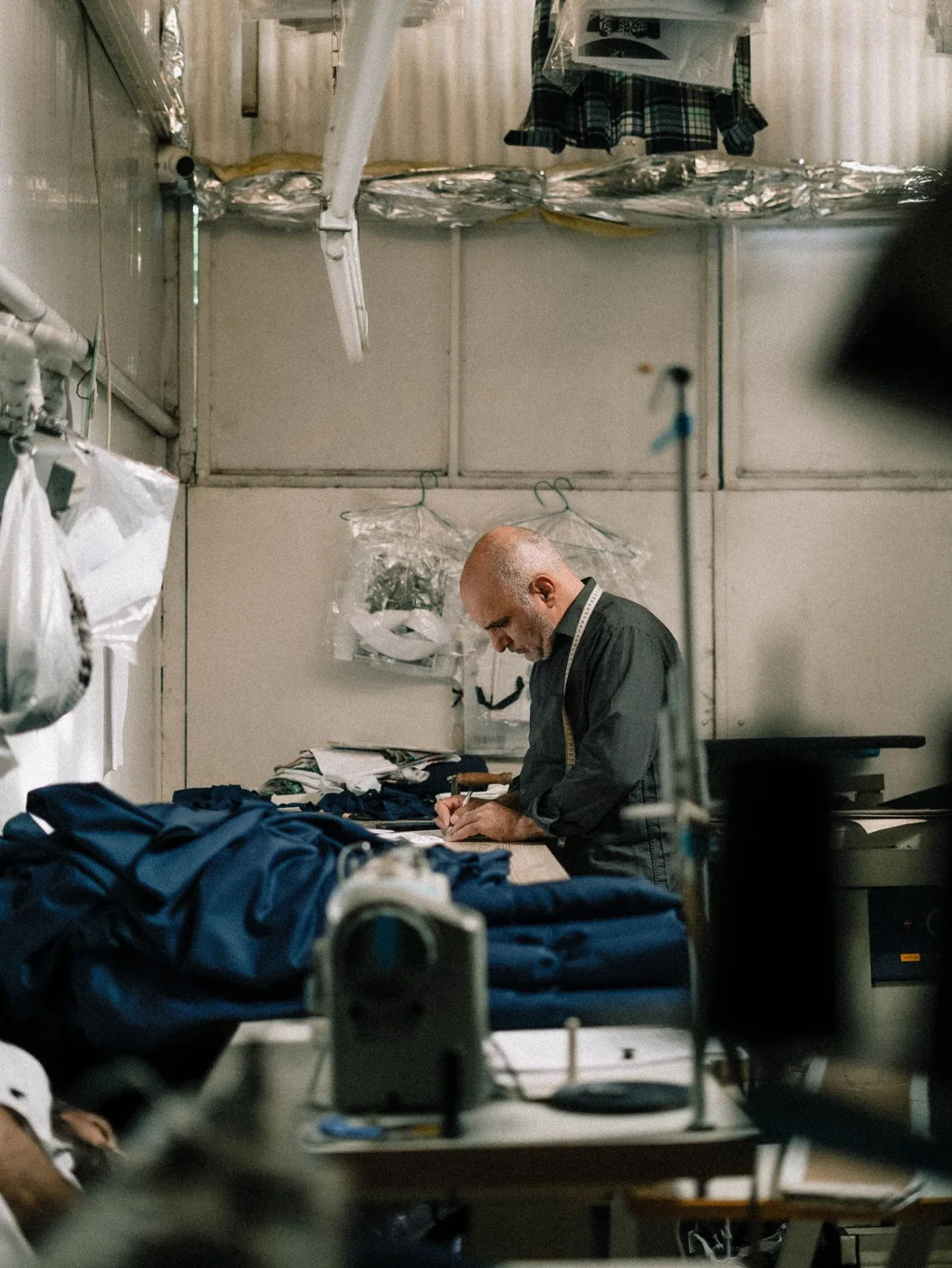 Tailor meticulously crafting garments in workshop