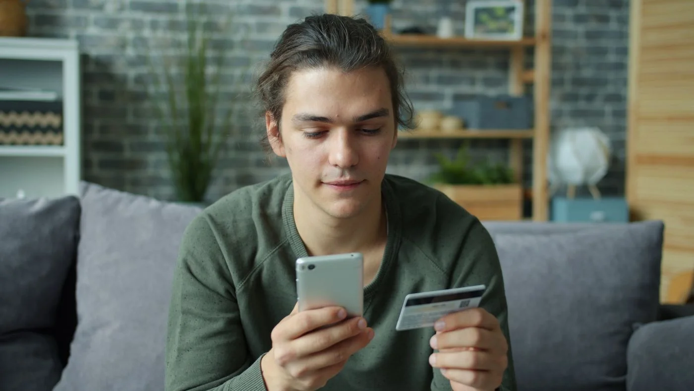 Young Man Shopping Online with Smartphone and Card